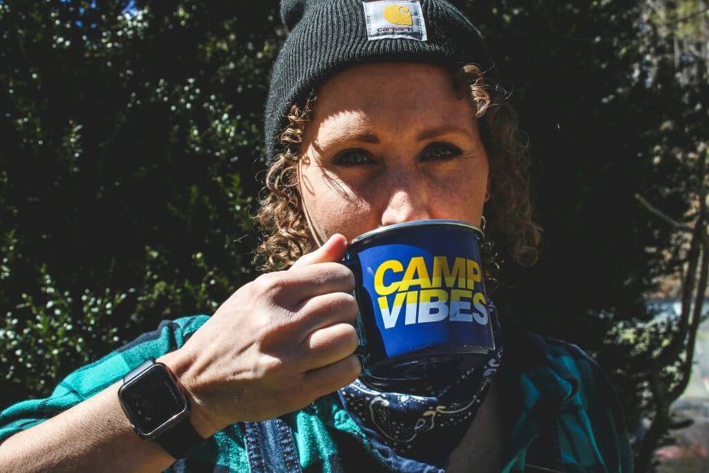 Jeune fille buvant dans un mug prière pour la France, devant un bosquet d’arbre