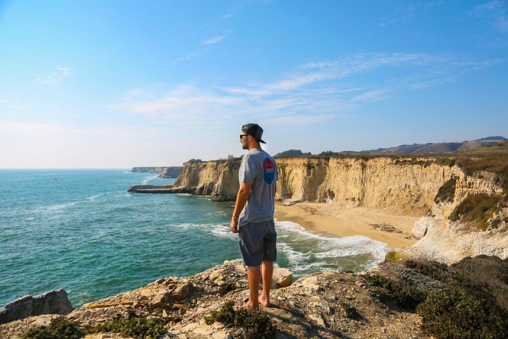 Jeune-homme en tshirt prière pour la France, de profil, sur une falaise, en bord de mer, regardant la mer